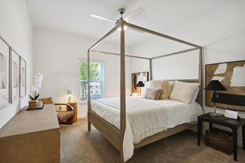 A bedroom with a four poster bed and a table with a lamp on it